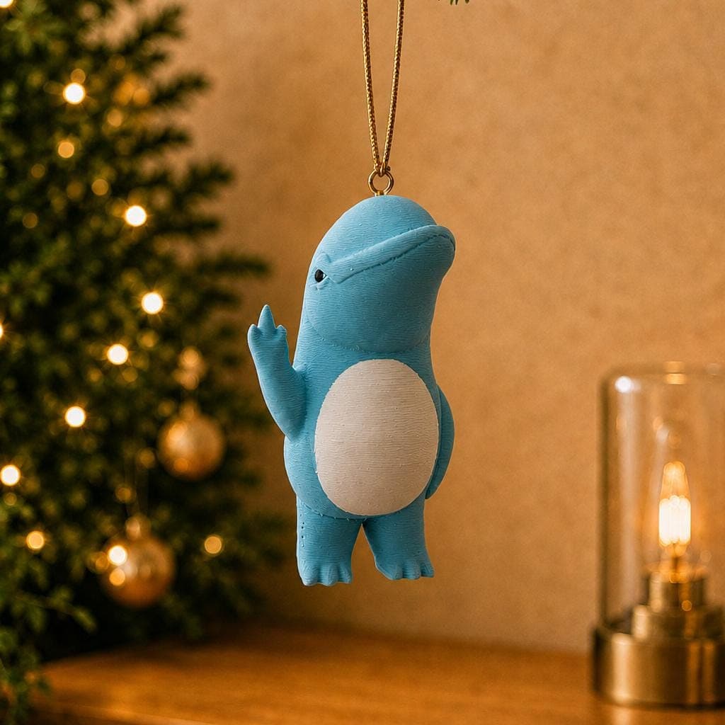Funny blue dolphin ornament hanging beside a decorated Christmas tree and warm lamp, with a rounded white belly and raised middle finger.
